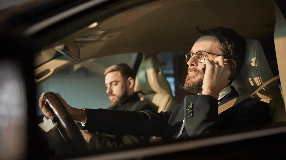 Two colleagues in a car, the driver smiling